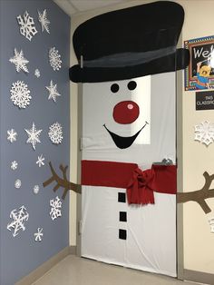 a snowman door decorated with paper snowflakes and a top hat on it