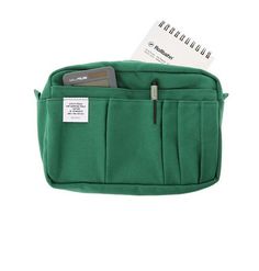 a green pencil case with a notepad and pen in the pocket on a white background