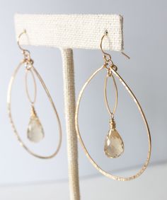 Our Genevieve Marquis Drop Earrings stand apart from the crowd. Featuring light reflecting faceted Beer Quartz stones floating inside sparkling hand forged gold fill teardrops, this style will add a striking statement to your look. All gold elements crafted from high quality 14k gold fill that will not wear off or discolor over time. MATERIALS Faceted Beer Quartz | Hand forged 14k gold fill teardrops and ear wires MEASUREMENTS2" drop from ear | 1.6" width approx. ORIGIN Handcrafted in Florida ST Elegant Gold Faceted Hoop Earrings, Gold Faceted Teardrop Hoop Earrings, Earrings Stand, Indigo Design, Beaded Earrings Diy, Earring Stand, Handmade Wire Jewelry, Feature Light, Quartz Stone