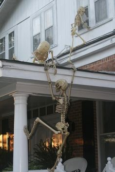 two skeleton statues on the front porch of a house, one is holding up his leg