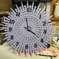 a clock made out of plastic sticks on top of a table next to a mirror