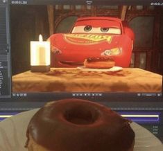 a donut sitting on top of a white plate next to a computer monitor with cars