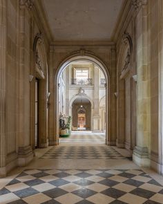 an empty hallway with checkered floor and arches