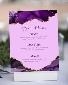 a menu card with purple flowers and gold trimmings is displayed on a table