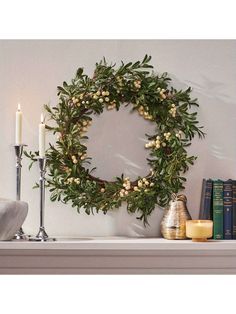 a wreath on a mantle with candles and books