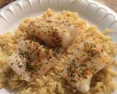 a white plate topped with rice covered in seared fish and garnished with seasoning