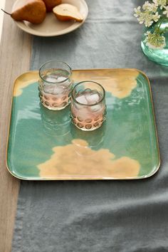 two glasses sitting on top of a green and yellow plate