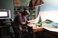 a man standing in front of a camera next to a table with fake trees on it