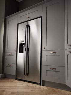 a stainless steel refrigerator in a kitchen with white cabinets and wood flooring on the side