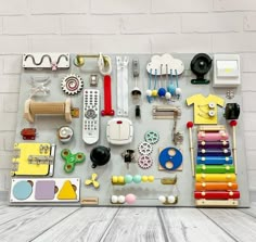 an assortment of crafting supplies displayed on a white brick wall with wood planks