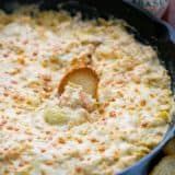 a casserole dish in a cast iron skillet with a spoon sticking out of it