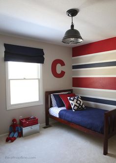 a child's bedroom decorated in red, white and blue with stripes on the walls