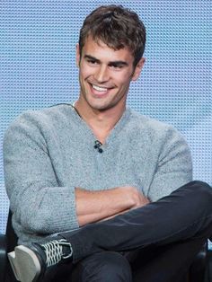 a man sitting in a chair with his arms crossed and looking at the camera while smiling