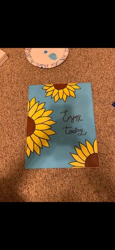 a birthday card with sunflowers on it sitting on the floor next to a cake