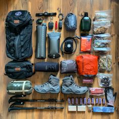 an assortment of hiking gear and equipment laid out on a wooden floor with the contents neatly organized