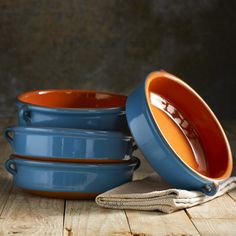 three blue and orange bowls sitting next to each other on a wooden table with one bowl in the middle