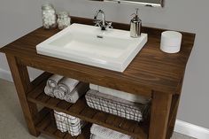 a bathroom with a sink, mirror and towels on the shelf in front of it