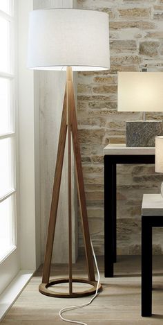 a lamp that is next to a table with a chair in front of it and a stone wall behind it