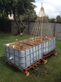 a large metal tub filled with hay on top of a wooden pallet in the grass