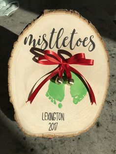 a wooden sign that says mistletoes next to a handprinted tree slice