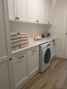 a washer and dryer sitting in a room next to white cupboards with candles on them