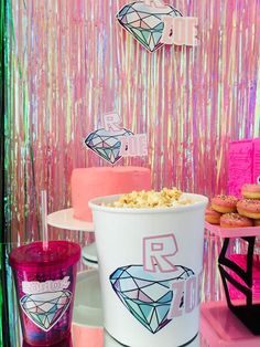 a table topped with lots of cakes and cupcakes next to a pink wall