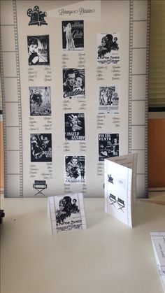 a white table topped with cards and pictures next to a wall covered in black and white photos