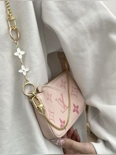 a woman holding onto a pink purse with butterflies on the handle and chain attached to it