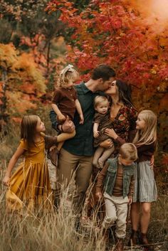 a group of people standing next to each other in front of trees with orange leaves