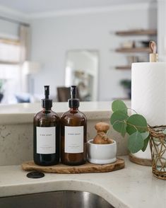 two bottles are sitting on a counter next to a toilet paper roll