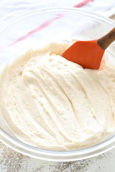 a wooden spoon in a bowl filled with white batter on top of a tablecloth