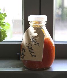 a jar filled with sauce sitting on top of a window sill