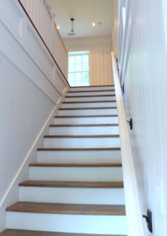 there is a set of stairs leading up to the second floor with white walls and wood handrails