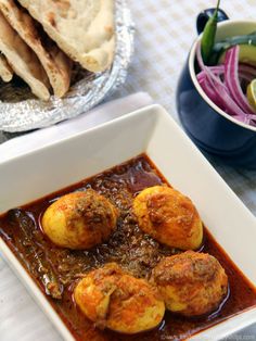 some food is in a white bowl on a table next to other plates and utensils