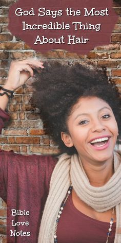 a woman with an afro standing in front of a brick wall and wearing a scarf