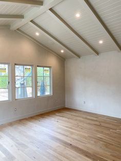 an empty room with wood floors and three windows