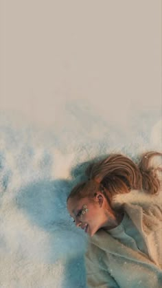 a woman laying on the ground with her hair in a ponytail and wearing a coat