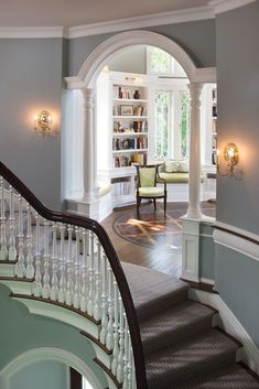 a staircase leading to a sitting area with bookshelves and chairs on either side