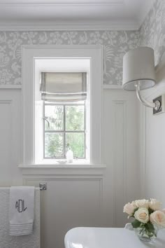 a white bathroom with floral wallpaper and window