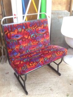 a colorful chair sitting next to a toilet in a room with other items on the floor