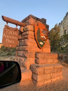 there is a sign for the national park in front of a rock wall and mountains