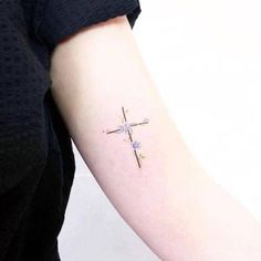 a small cross tattoo on the arm