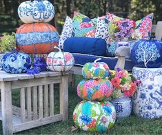 colorful pillows and vases are on display in the grass near an old wooden bench