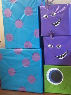 three boxes decorated like monsters sitting on the floor with purple and green wrapping around them