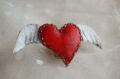 a red heart with angel wings on a white cloth