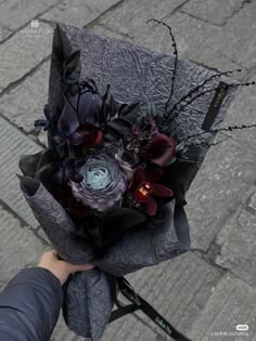 a person holding a bouquet of flowers on top of a stone walkway in front of a building