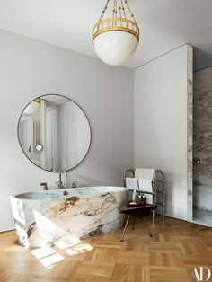 a bathroom with a marble bathtub and round mirror