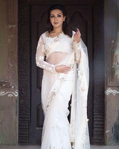 a woman wearing a white sari with sheer sleeves