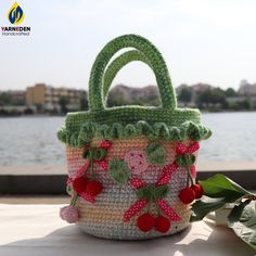 a crocheted purse sitting on top of a table next to a body of water