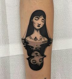 a woman's face with her reflection in the water tattoo on the left leg